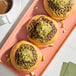 A plate of Kontos kataifi pastries with green toppings on a table.