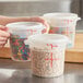 A set of translucent round polypropylene food storage containers with lids, each marked with measurement lines and filled with various food items.