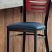 A Lancaster Table & Seating navy vinyl padded seat on a metal frame chair.