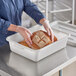 A white polypropylene bus tub being used to hold loaves of bread.