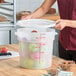 A large translucent round polypropylene food storage container with a lid and red measurement markings.