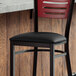 A Lancaster Table & Seating black vinyl padded seat on a metal frame.