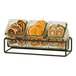 A Cal-Mil black metal display with 3 square glass jars containing orange and lemon slices.