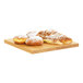 A Cal-Mil square oak wood serving board with pastries on it.