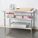 A stainless steel adjustable undershelf designed for 30" x 48" work tables, shown installed on a kitchen prep table.