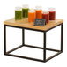 A black metal rectangular display riser on a table with glasses of juice on it.