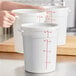 A set of white round polypropylene food storage containers with lids and red measurement markings.