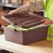 A brown polyethylene utility lid being placed on a storage container.
