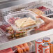 A hand holding a Choice clear plastic 3-compartment container with a sandwich inside.