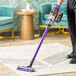 A hand using a Dyson V11 cordless stick vacuum to clean a rug.