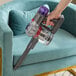A person using a Dyson Cordless Hand Vacuum to clean a chair.