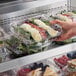 A hand holding a Choice clear plastic clamshell container of food.