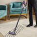 A person using a Dyson V8 cordless stick vacuum to clean a carpet.