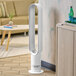 A white Dyson tower fan in a white room next to a couch.