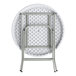 A round, granite white plastic folding table with gray metal legs shown in a folded position.