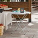 A 32-inch round granite white plastic folding table with gray legs.