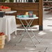 A 24-inch round granite white plastic folding table with gray legs, designed for standard height and heavy-duty use.