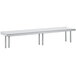 A stainless steel rectangular table mounted shelf with two legs on a long metal table.