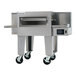 A commercial stainless steel conveyor oven with a wide belt and caster wheels, designed for high-volume cooking.
