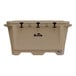 A tan Grizzly Cooler with black handles on a table outdoors.
