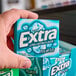 A hand holding a case of Wrigley's EXTRA Polar Ice gum packets.