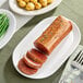 A plant-based vegan whole-cut loin partially sliced and served on a white platter.