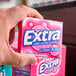 A hand holding a pink box of Wrigley's EXTRA bubble gum.
