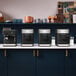 A row of black and silver KitchenAid espresso machines on a counter.