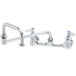 A chrome T&S wall mount faucet with two handles and a double joint nozzle.