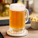 A glass of beer with foam on a wooden bar.