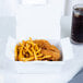 A white Southern Champion take-out box filled with chicken and french fries on a table.
