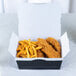 A Southern Champion paper take-out box filled with fried chicken and french fries on a table.