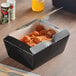 A Southern Champion black paper take-out box filled with spaghetti and meatballs.