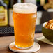 A glass of beer on a table with a Hopzoil MAJIK® Cascade Hop Extract coaster.