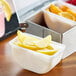 A white container of Dole lemon wedges on a table with bowls of lemons and oranges.