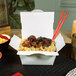 A white Southern Champion paper take-out box filled with food and chopsticks.