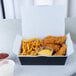 A Southern Champion paper take-out box filled with fried chicken and french fries on a table.