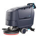 A compact Nilfisk walk-behind floor scrubber with wheels.