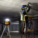 A man on a ladder using a DCL074 work light to work on a ceiling.