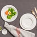 A white Jungle Decor compostable sugarcane pulp plate with food on it next to a fork and knife.
