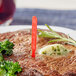 A steak with a Royal Paper red rare steak marker in the middle of it on a plate with broccoli and a fork.