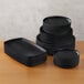 A stack of American Metalcraft black melamine plates on a table.