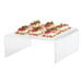 A group of food on a clear Cal-Mil U-shape display riser.