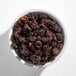 A white bowl filled with dried flame raisins.