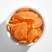 A white bowl filled with orange dried mango slices.