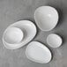 An assortment of matte white oval bowls and plates from the Organica by Fortessa Vitraluxe collection.