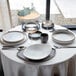 A set of white round stoneware cups placed on a table set for dining.