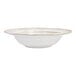 A white stoneware soup bowl with a scalloped and embossed floral edge.