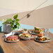 A round ivory melamine plate displayed on a wooden table with food and other dishes.