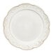 A close up of a Mannette Floral by Fortessa white stoneware dinner plate with a scalloped and floral edge and gold trim.